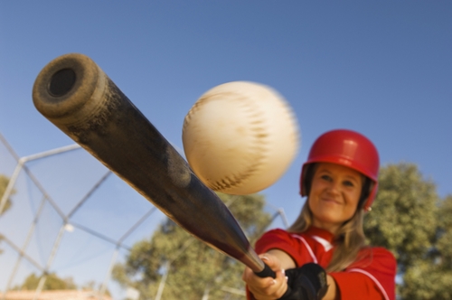 woman swinging bat at softball