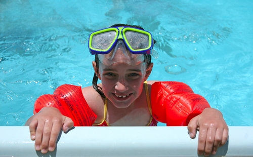 smiling boy in water holding on to side of pool