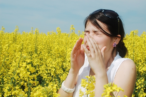 sneezing woman surrounded by tall flowers