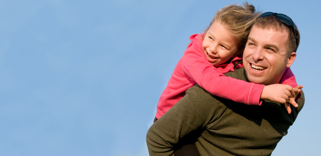 young girl holding on to fathers shoulders as both smile