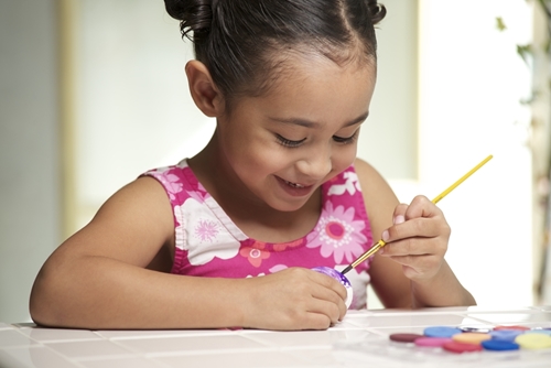 a smiling girl painting with craft materials