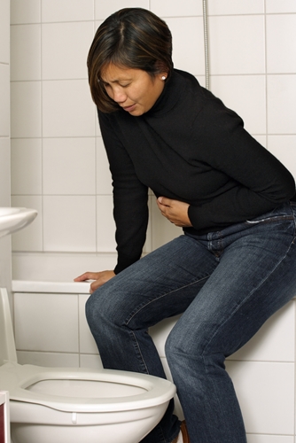 lady sits on edge of tub holding her stomach