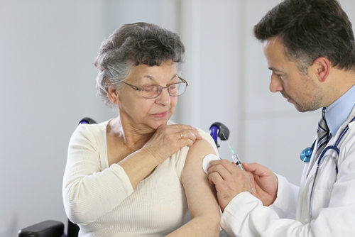 older woman receives annual flu vaccine from her doctor