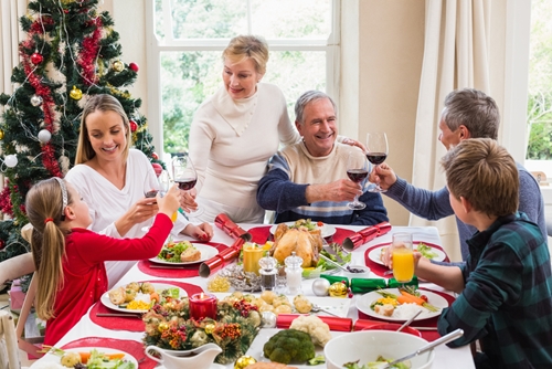 an older man and woman with their children and grandchildren sit for a holiday meal