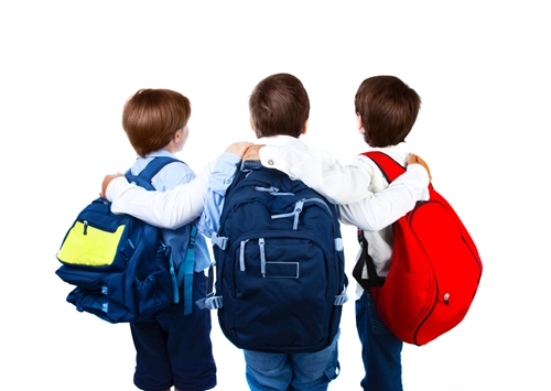 three children in book bags return to school post-winter