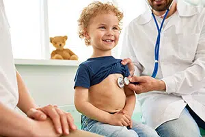 A young boy is receiving pediatric care by a doctor during an examination