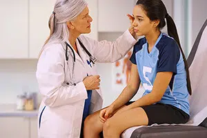 A female doctor is talking to a young female patient on an exam table